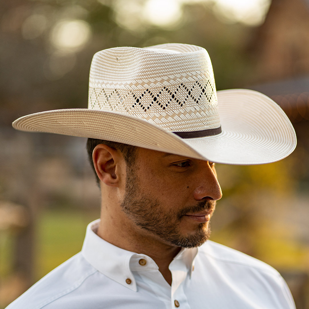 A man wearing a white Shantung straw cowboy hat and a while western dress shirt.