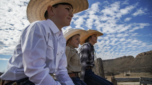 children with straw hats sitting on fence