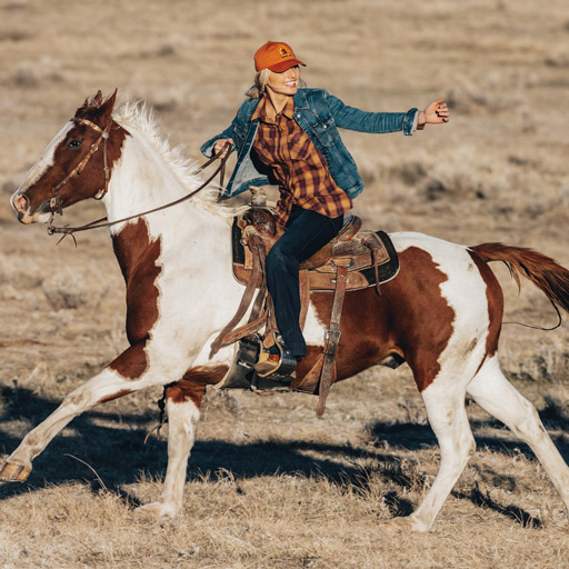 cowgirl riding horse in jeans and boots